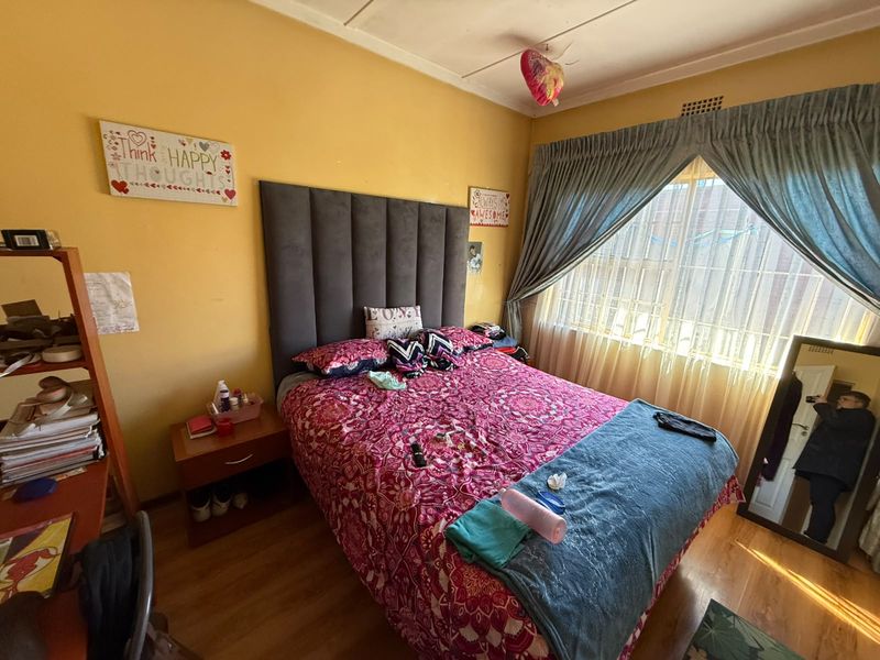 A bedroom featuring laminate flooring and window treatments, providing a functional space with potential for modernization.