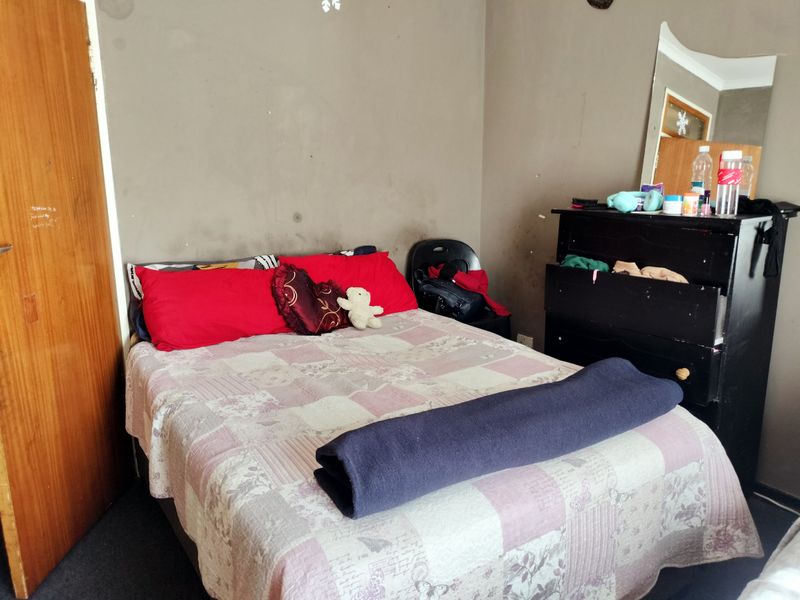 A bedroom featuring a wooden door and walls showing significant signs of wear and staining, requiring cosmetic attention.
