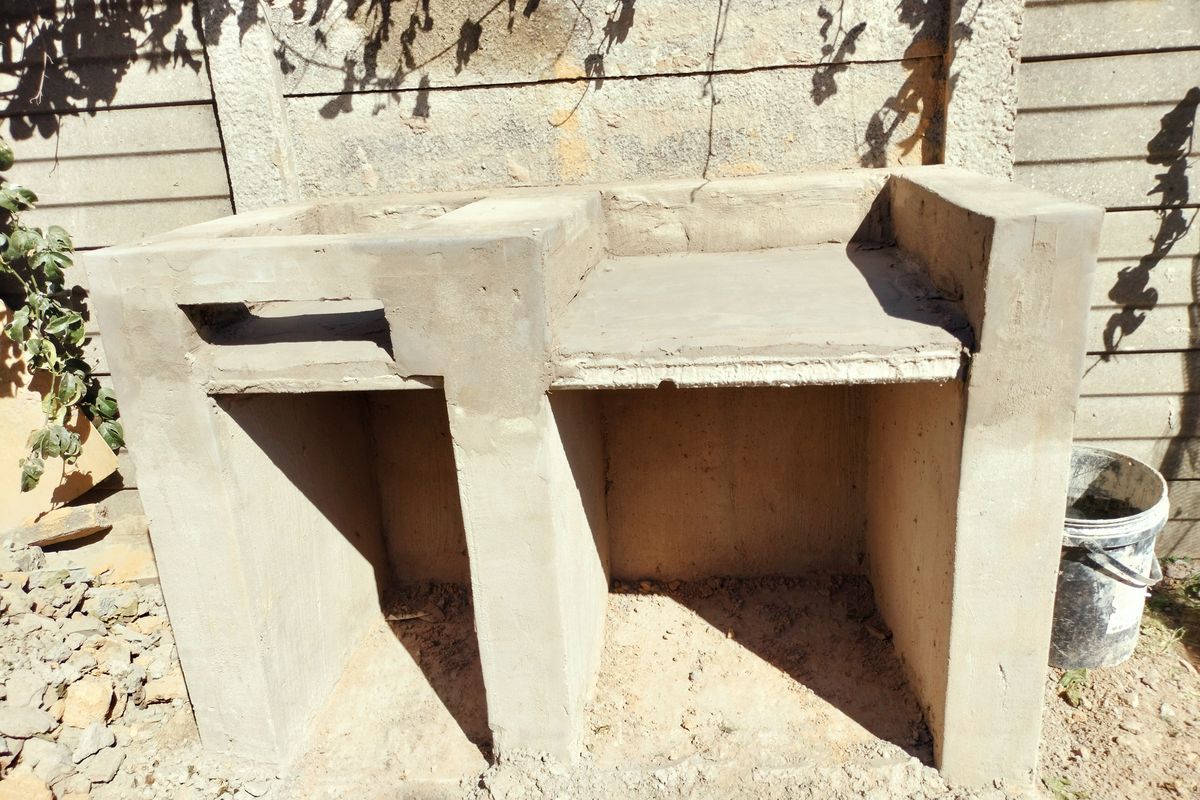 An unfinished built-in concrete braai structure located in the rear garden area, awaiting final finishes and installation.
