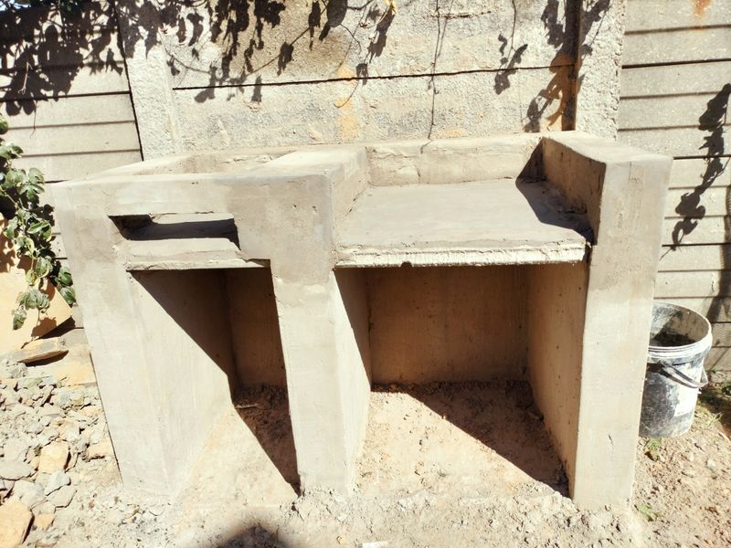 An unfinished built-in concrete braai structure located in the rear garden area, awaiting final finishes and installation.