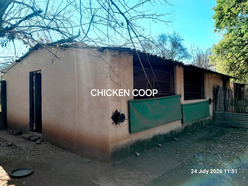 A functional farm utility structure, currently utilized as a chicken coop, featuring masonry walls and metal mesh ventilation panels.