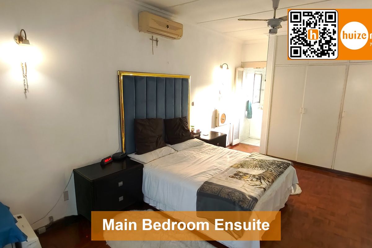 Spacious main bedroom featuring parquet flooring, built-in cupboards, wall-mounted air conditioning, and an ensuite bathroom.
