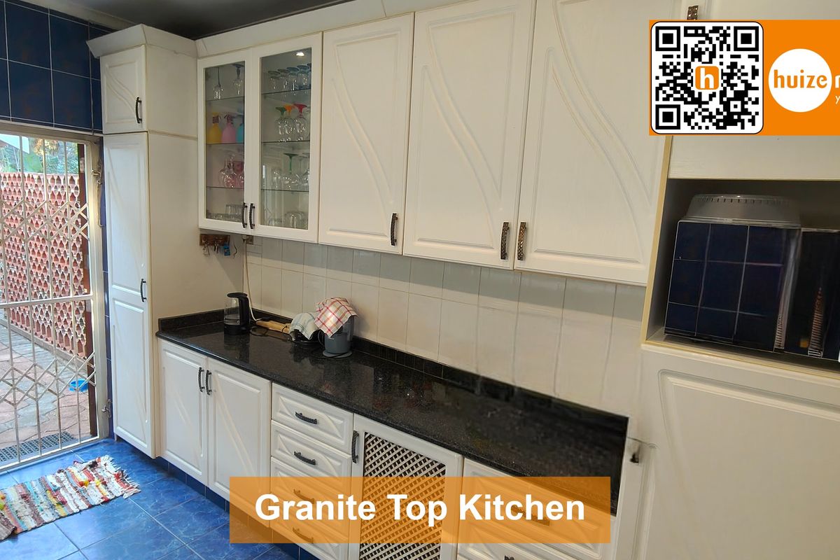 Kitchen featuring white cabinetry, granite countertops, and a tiled backsplash, with direct access to an outdoor area through a security gate.