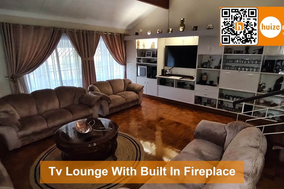 Spacious living room featuring parquet flooring, a vaulted ceiling, and extensive built-in cabinetry for storage and display.