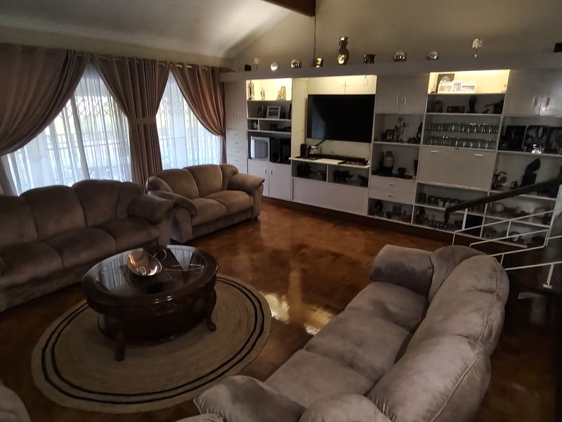 Spacious living room featuring vaulted ceilings, parquet flooring, and extensive built-in cabinetry with integrated shelving.