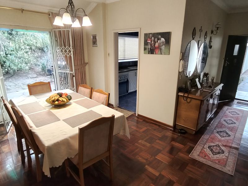 Dining room featuring classic parquet flooring, coved ceilings, and direct access to the rear garden through a sliding security door.