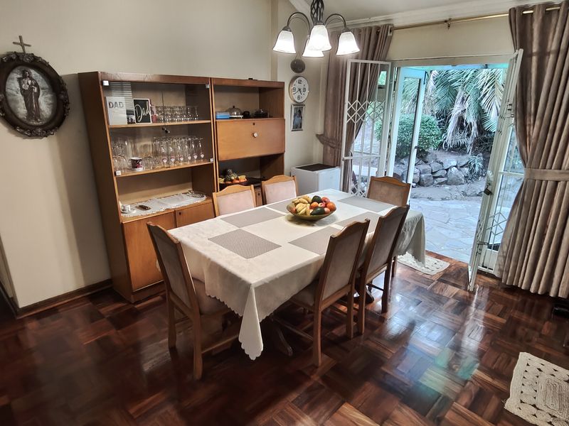 Dining room featuring polished parquet flooring and direct access to the rear garden through a sliding glass door.