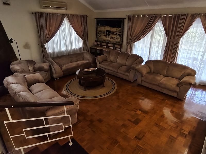 Spacious living room featuring polished parquet flooring, a built-in fireplace, and large sliding doors providing access to the exterior.