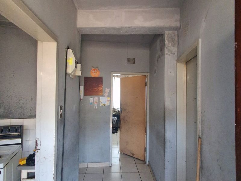 A narrow hallway featuring tiled flooring and visible wall wear, requiring cosmetic updates and maintenance to improve the overall condition of the space.