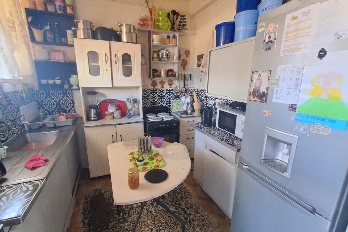 A compact kitchen featuring built-in cabinetry, a stainless steel sink, and a patterned backsplash, offering potential for a modern renovation.