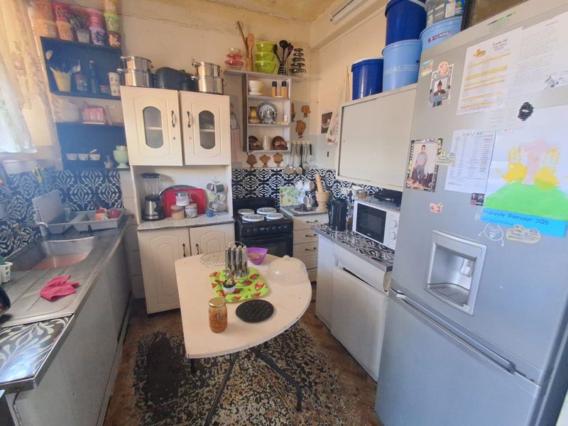 A compact kitchen featuring built-in cabinetry, a stainless steel sink, and a patterned backsplash, offering potential for a modern renovation.
