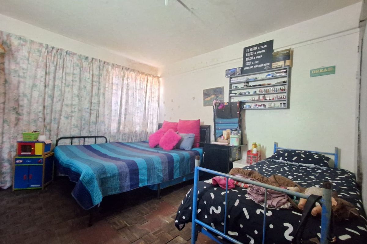 A bedroom featuring parquet flooring and large windows with curtains, requiring cosmetic updates to improve the overall condition and appeal.