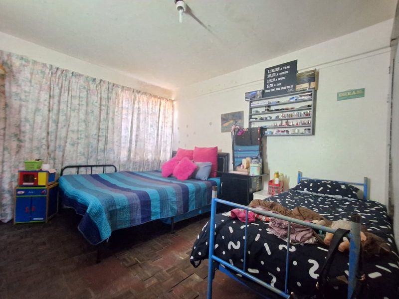 A bedroom featuring parquet flooring and large windows with curtains, requiring cosmetic updates to improve the overall condition and appeal.