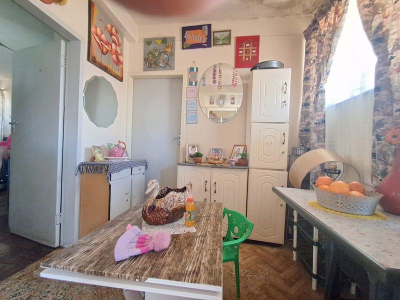 A dining area featuring parquet flooring and built-in cabinetry, showing signs of ceiling water damage and general wear.