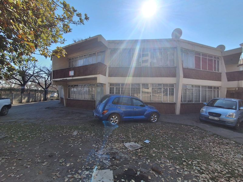 Front elevation of a multi-story flat complex featuring metal-framed windows and a concrete balcony structure.