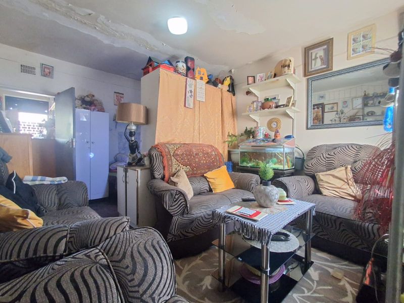 A living room area featuring built-in shelving, currently showing significant signs of ceiling water damage and peeling paint requiring maintenance.