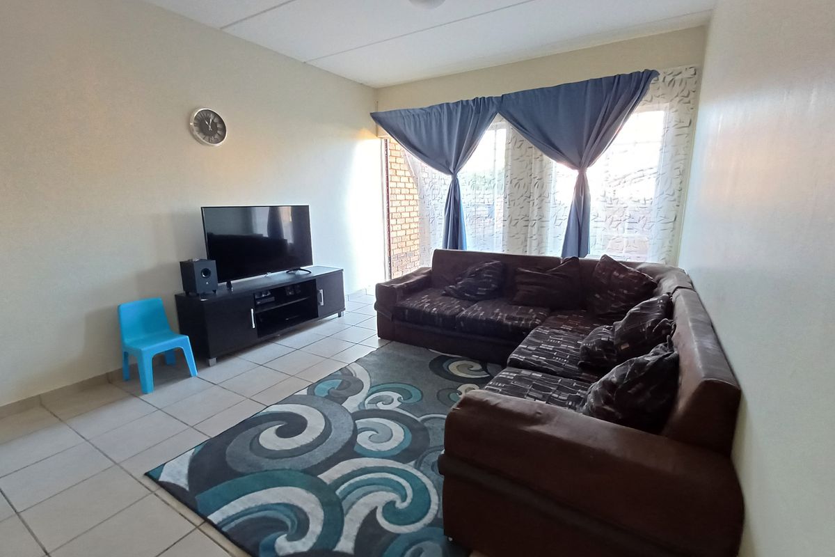 A functional living room featuring tiled flooring and natural light from the window, providing a comfortable space for relaxation.