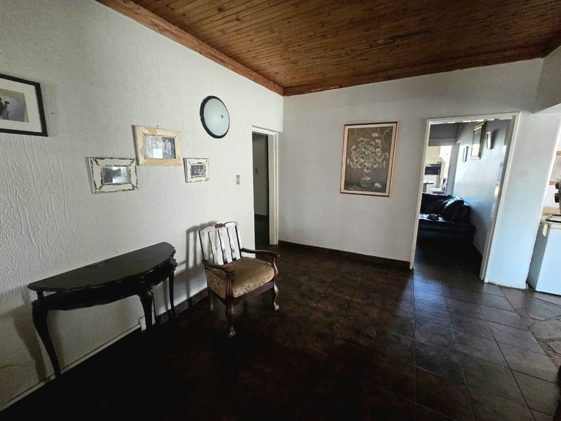 A living area featuring dark tiled flooring and a natural timber ceiling, providing a neutral base for potential interior updates.
