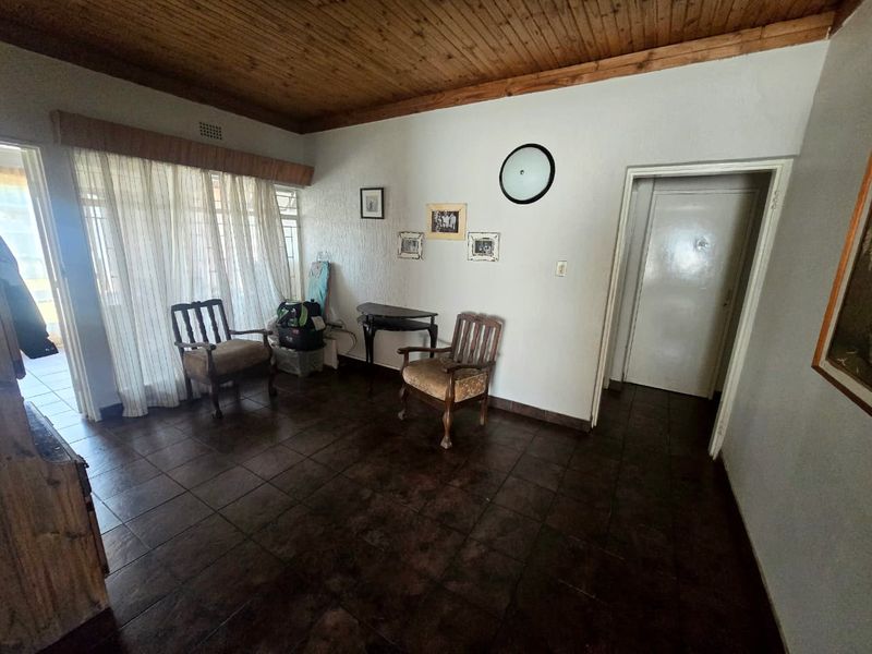 A living area featuring dark tiled flooring and a timber tongue and groove ceiling, providing a dated aesthetic ready for modernization.