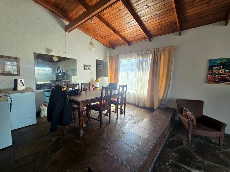Dining area featuring a vaulted timber ceiling, flagstone flooring, and a built-in tiled bench, offering a rustic aesthetic with potential for modern updates.