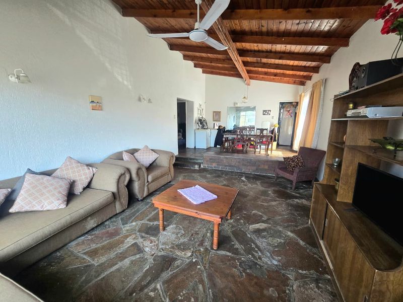 Open plan living and dining area featuring rustic flagstone flooring and a high exposed timber beam ceiling with a ceiling fan.
