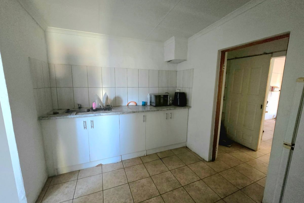 A functional kitchen featuring white cabinetry, tiled backsplash, and ceramic flooring, offering a blank canvas for modern updates and renovation.