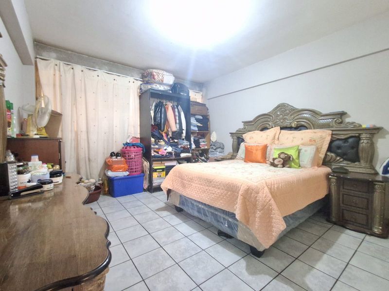 A bedroom featuring ceramic tile flooring and a central ceiling light fixture, requiring cosmetic updates to the walls and ceiling finishes.