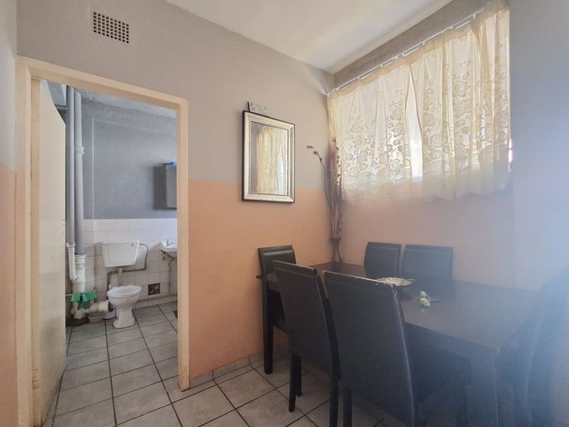 Dining area featuring tiled flooring and two-tone wall paint, with an adjacent bathroom visible through the doorway.
