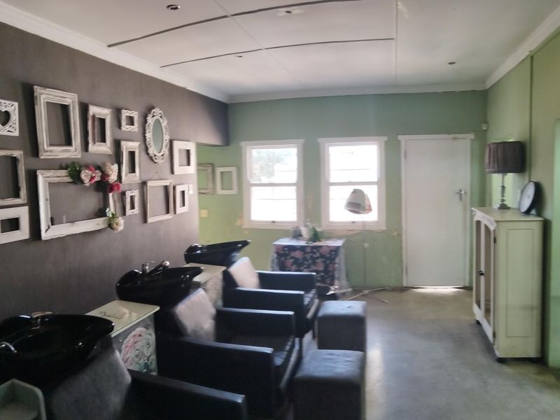 A utility space currently configured as a salon, featuring built-in wash basins, recessed lighting, and visible wall surface wear requiring maintenance.