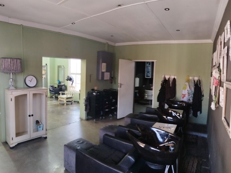 Commercial salon space featuring concrete flooring, recessed lighting, and multiple plumbed wash basins, currently configured for professional hair services.