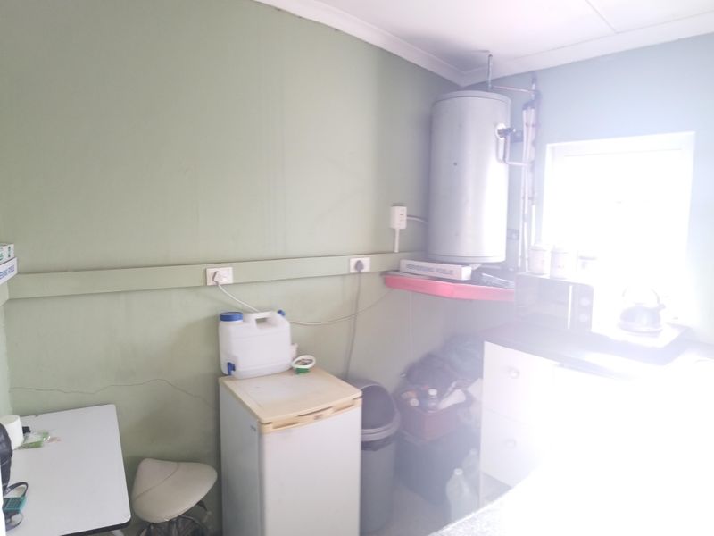 A utility or laundry area featuring an exposed electric water heater, plumbing connections, and wall-mounted electrical outlets.