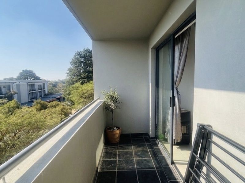 A private balcony featuring dark tiled flooring, a metal balustrade, and sliding glass door access, offering an elevated view of the surrounding area.