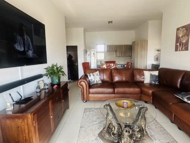 An open-plan living area featuring tiled flooring and a connected kitchen space with built-in cabinetry.