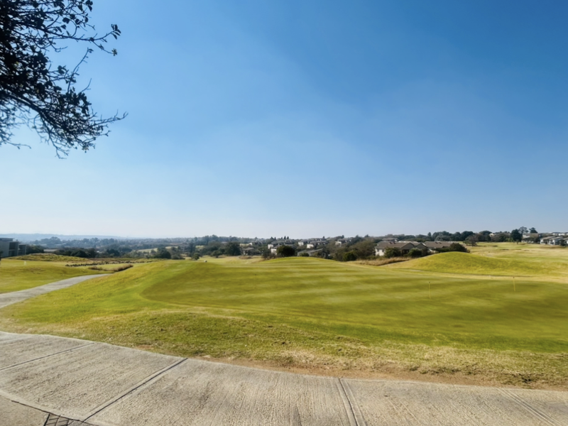 A scenic view overlooking a well-maintained golf course with a paved pathway in the foreground.