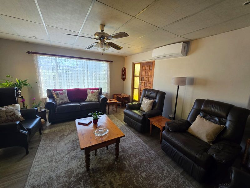 A comfortable living room featuring a ceiling fan, split-system air conditioning, and laminate flooring, providing a functional and relaxed space.