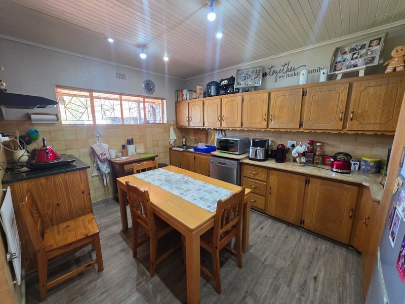 A functional kitchen featuring traditional wooden cabinetry, laminate countertops, tiled backsplash, and a timber ceiling, offering a classic aesthetic with potential for modernization.