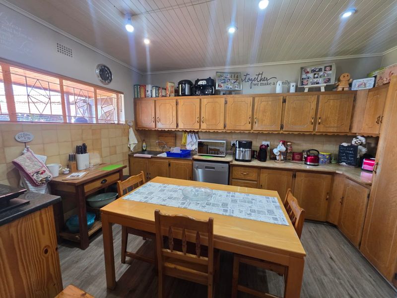 A functional kitchen featuring traditional wooden cabinetry, laminate countertops, tiled backsplash, and a timber panelled ceiling with recessed lighting.