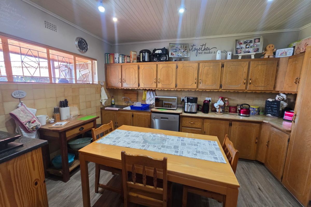 A functional kitchen featuring traditional wooden cabinetry, laminate countertops, tiled backsplash, and a timber panelled ceiling with recessed lighting.