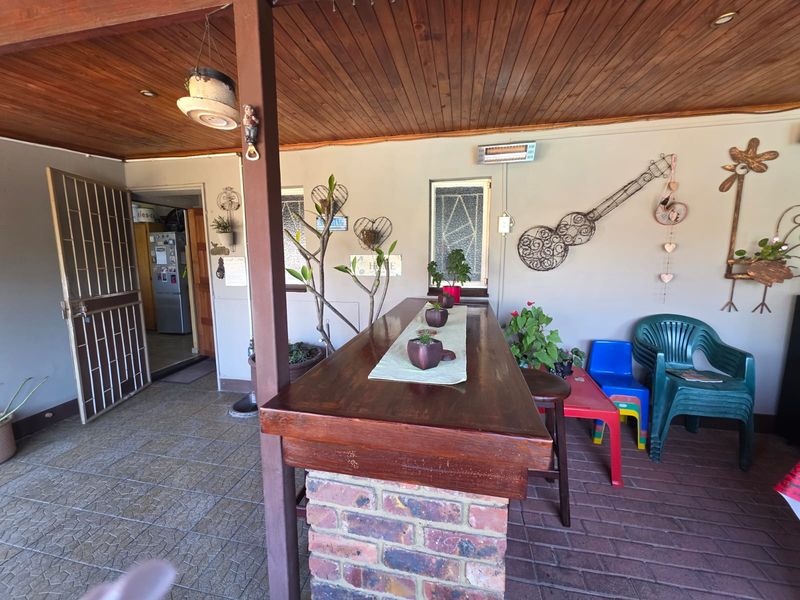 Covered patio area featuring a built-in brick bar counter, timber ceiling, and direct access to the kitchen through a security gate.