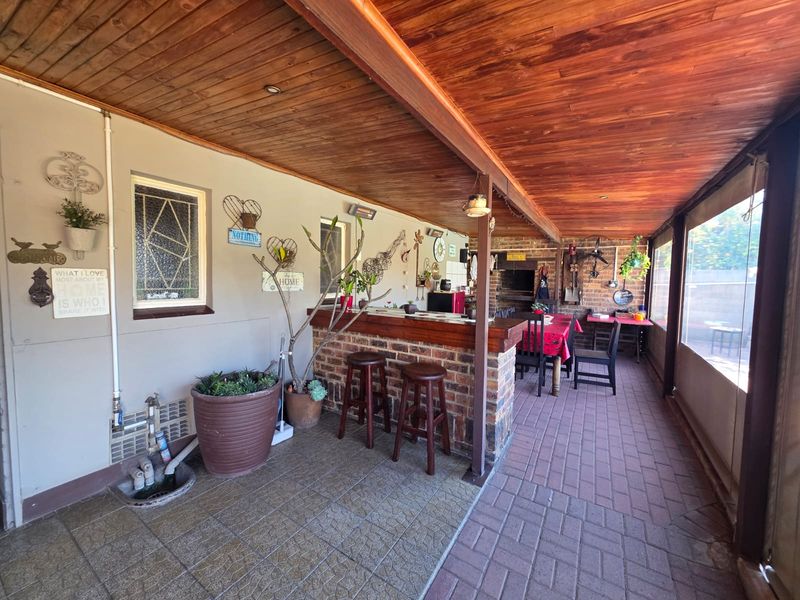 Covered patio area featuring a built-in brick bar, integrated braai, timber ceiling, and paved flooring, ideal for outdoor entertaining.