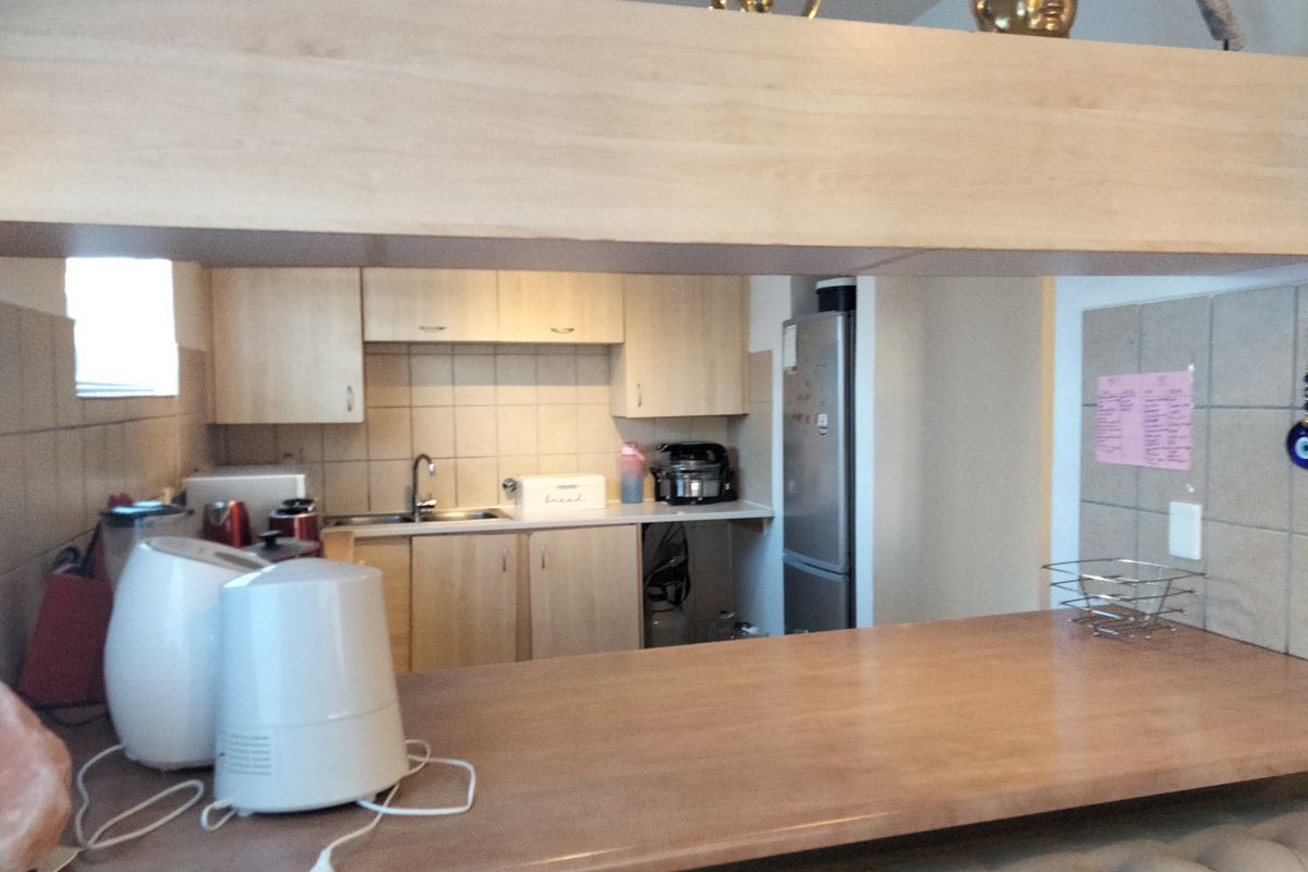 A functional kitchen featuring light wood-finish cabinetry, tiled backsplash, and a convenient breakfast bar counter for casual dining.