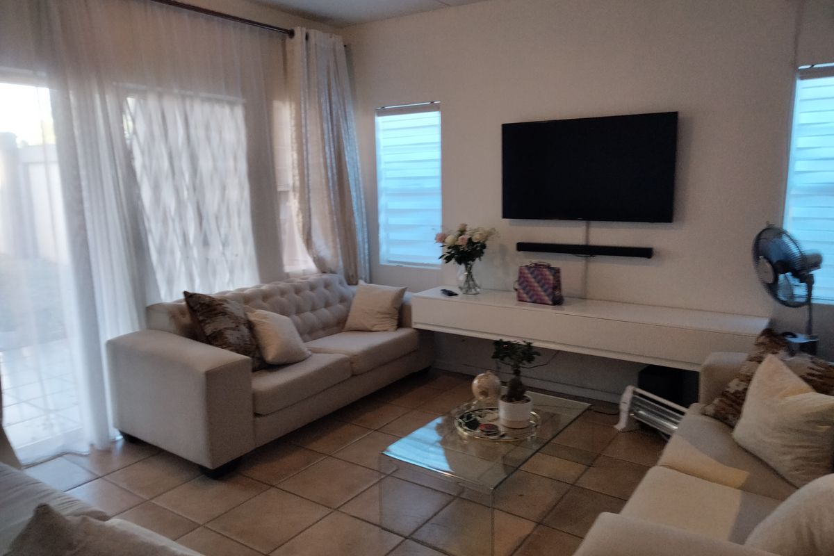 A comfortable living room featuring tiled flooring, a wall-mounted floating console, and large sliding glass doors providing access to the exterior.