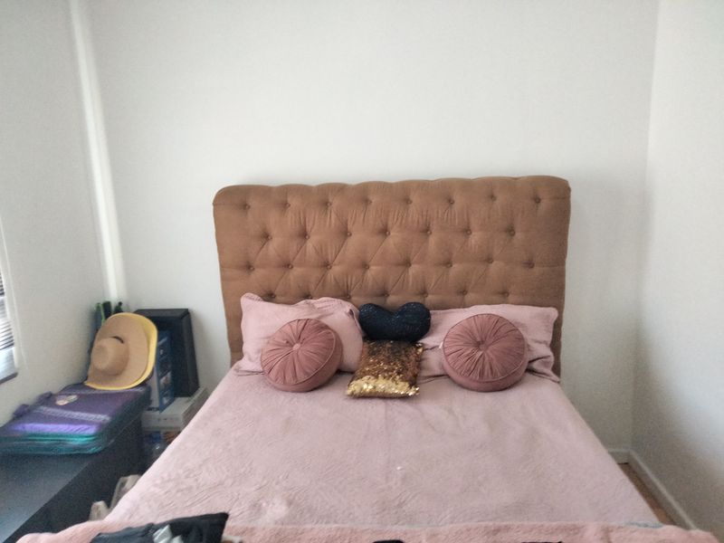 A bedroom featuring a tufted headboard and neutral wall finishes, providing a functional sleeping space.