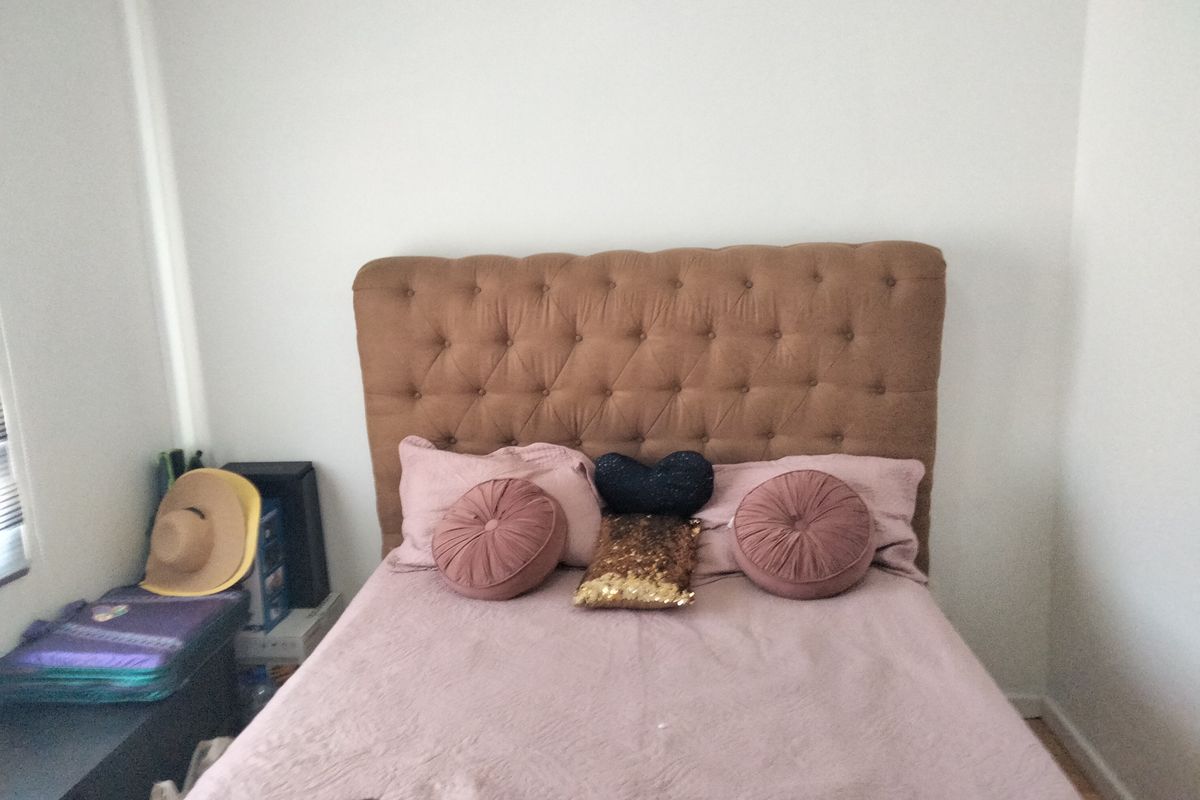 A bedroom featuring a tufted headboard and neutral wall finishes, providing a functional sleeping space.