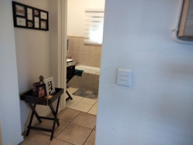 A view from a hallway looking into a bathroom with tiled flooring and a light switch on the wall.