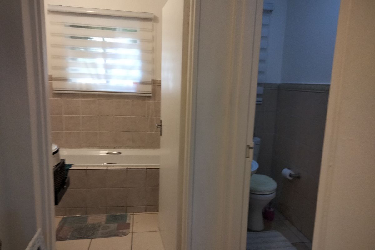 A functional bathroom featuring a bathtub, toilet, and basin with neutral wall and floor tiling.