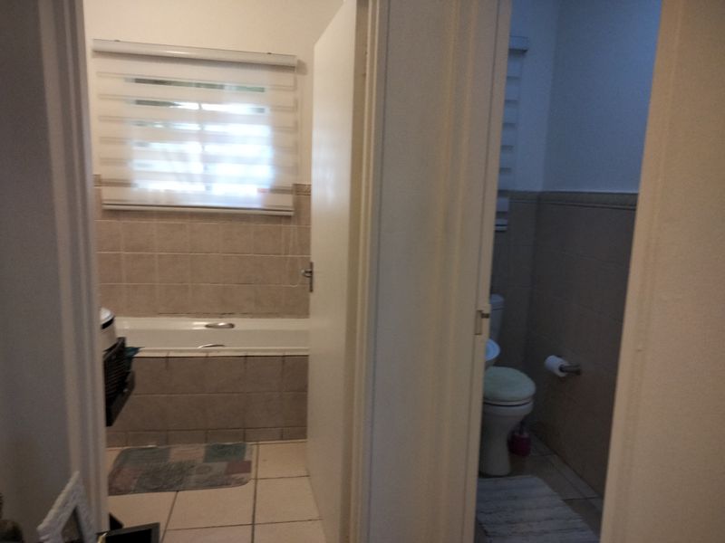 A functional bathroom featuring a bathtub, toilet, and basin with neutral wall and floor tiling.