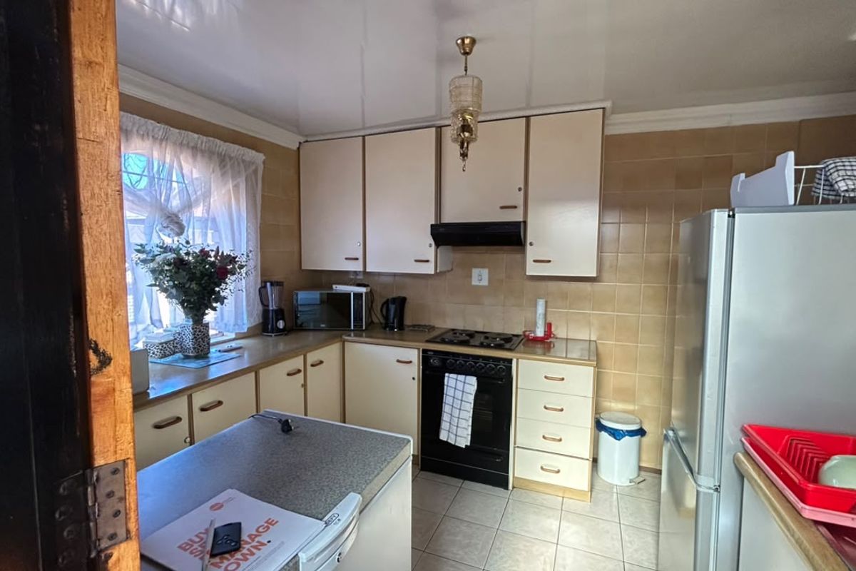 A functional kitchen featuring built-in cabinetry, tiled splashbacks, and integrated cooking appliances, offering a practical layout with potential for modern updates.