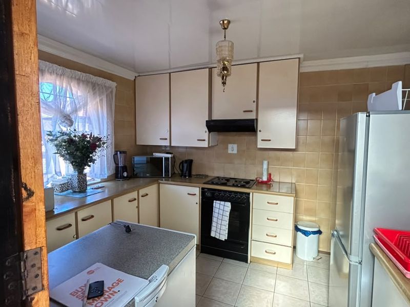 A functional kitchen featuring built-in cabinetry, tiled splashbacks, and integrated cooking appliances, offering a practical layout with potential for modern updates.