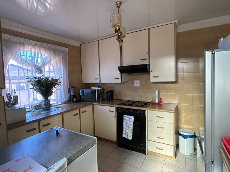 A functional kitchen featuring laminate cabinetry, tiled backsplash, built-in oven with gas hob, and tiled flooring, offering a classic layout with potential for modernization.